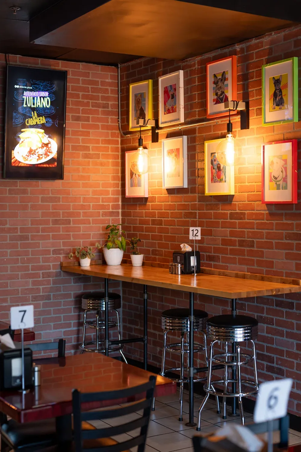 The brick wall at Duluth, hung with framed dog portraits above a high-top counter